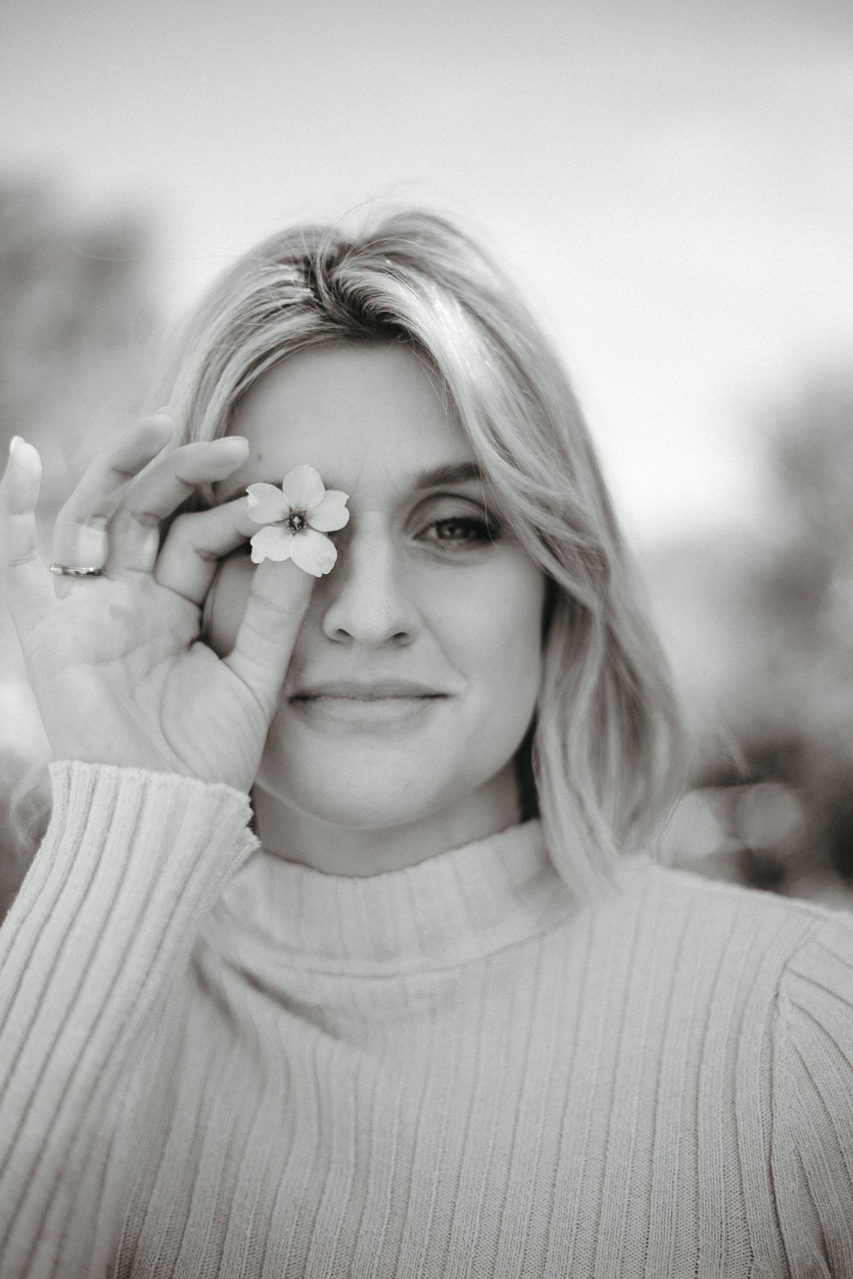 Schwarzweißes Porträt einer Frau mit Blume am Auge – SULIA Doula Akademie
